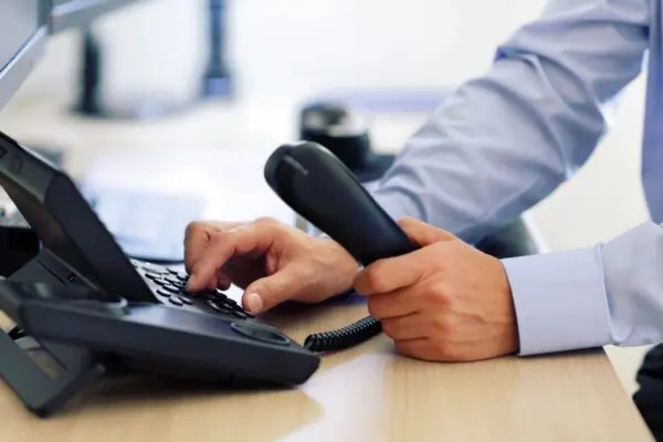 A person is holding a phone and typing on the keyboard.