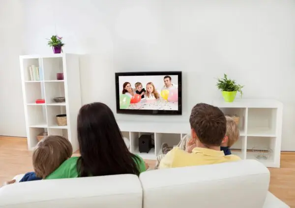 A group of people sitting on top of a white couch.