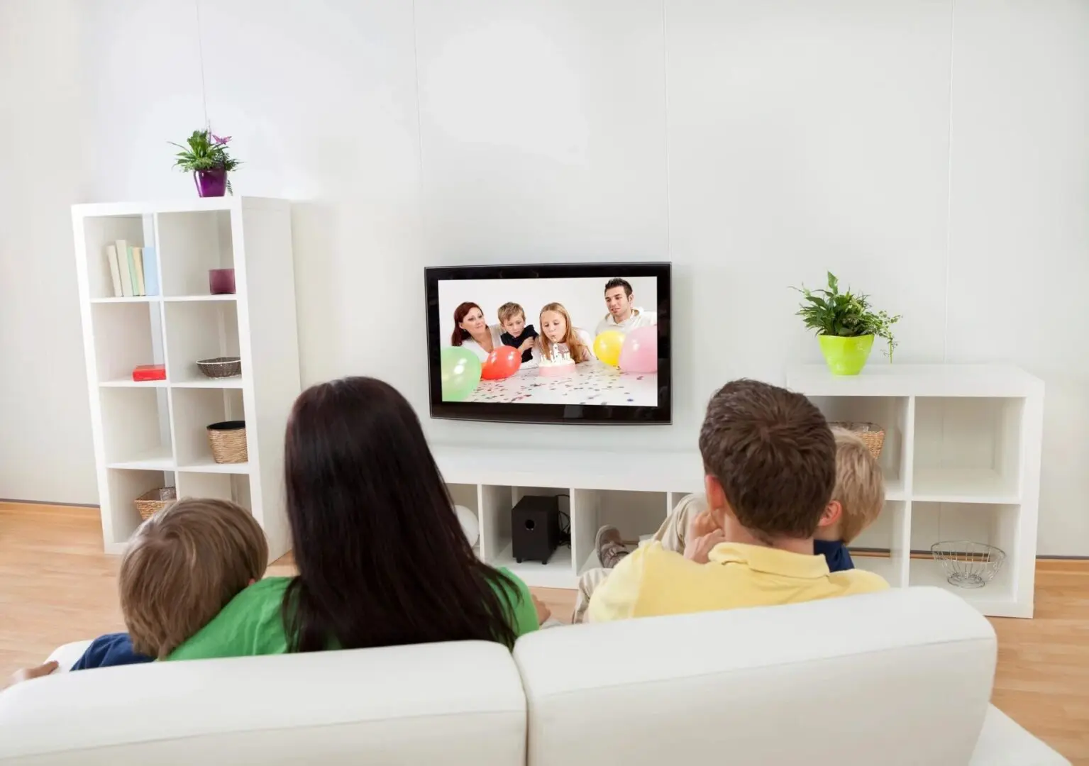 A group of people sitting on top of a white couch.