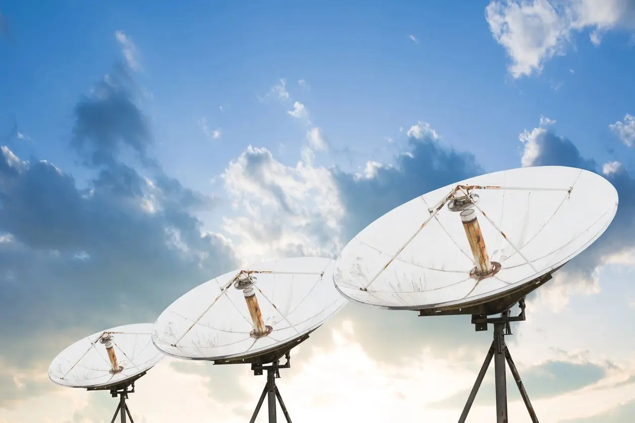 A group of satellite dishes sitting in front of the sky.